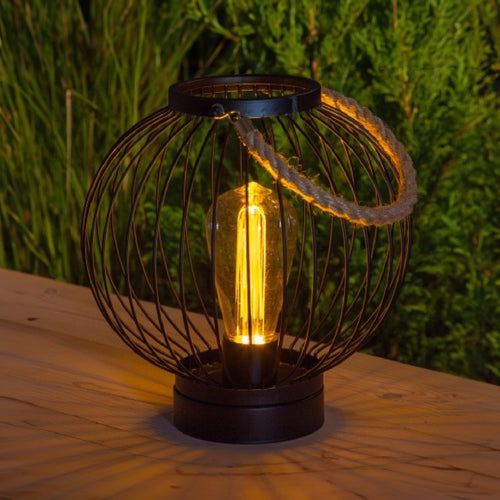 A round metal lantern with an LED filament bulb in the middle.