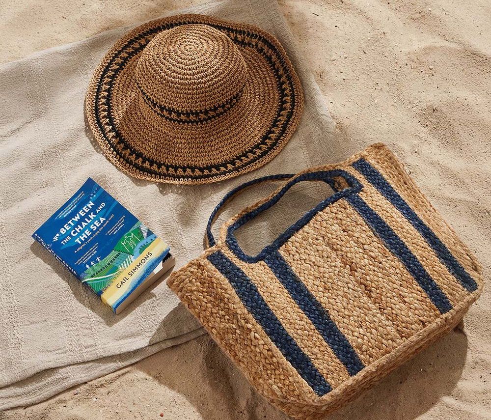  Woven bag, straw hat, and book on sand 