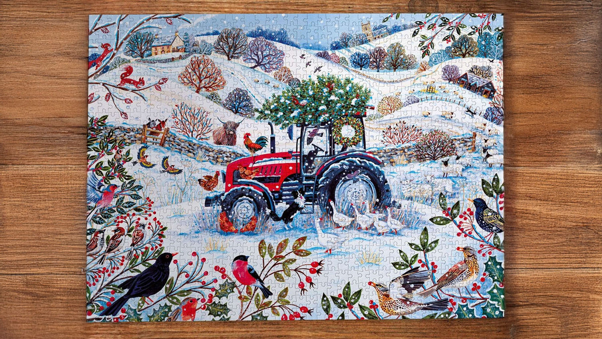  A completed jigsaw puzzle featuring a winter farm scene with a red tractor, snowy hills, birds, and festive foliage, displayed flat on a brown wooden surface. 