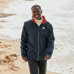 A man wearing a navy RNLI jacket with a red collar lining. It has the RNLI flag on the left chest. 