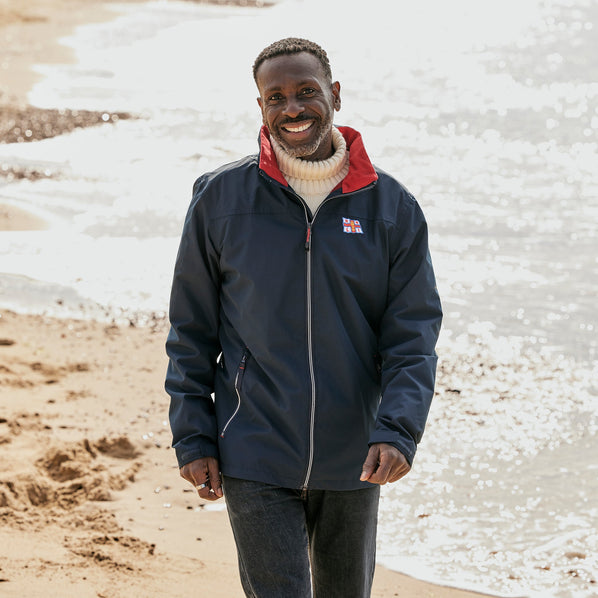 A man wearing a navy RNLI jacket with a red collar lining. It has the RNLI flag on the left chest. 