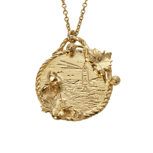A gold Alex Monroe pendent with an engraved design of a lighthouse in a storm. 