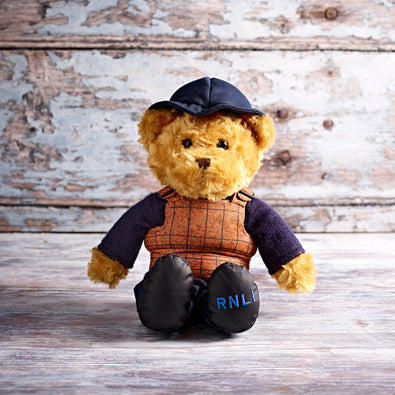 A teddy bear wearing a navy hat and coat, along with a cork lifejacket
