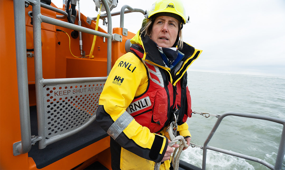  RNLI Crew member wearing an RNLI life jacket and helmet, full crew kit on an RNLI boat. 