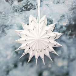 White paper snowflake hanging against a snowy background