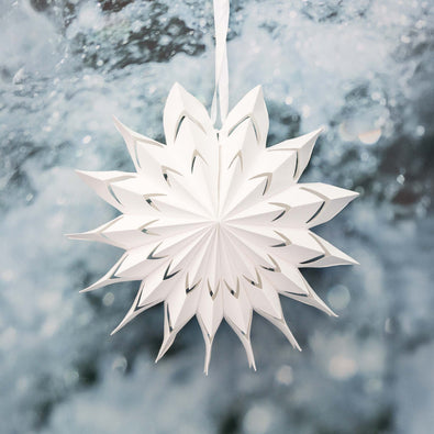 White paper snowflake hanging against a snowy background