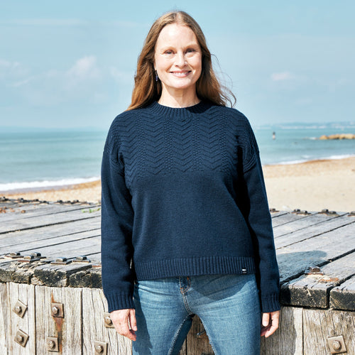 A woman on the beach wearing the Women's RNLI + Finisterre Polperro Jumper in navy.