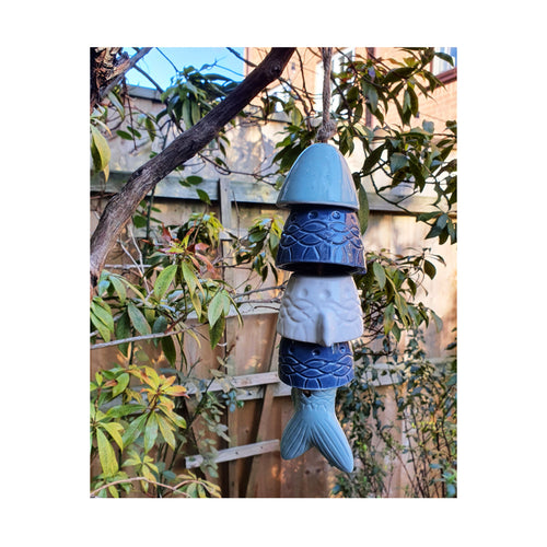 Outdoor Hanging Fish Chime hung on a branch in a garden.