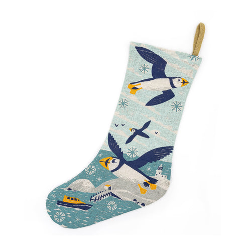 RNLI Christmas Flying Puffin Stocking with an illustrated design of puffins flying above a lighthouse with an RNLI lifeboat at sea.