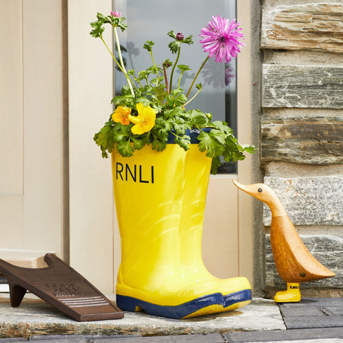 A planter in the shape of a pair of RNLI lifeboat crew wellies in yellow and navy.