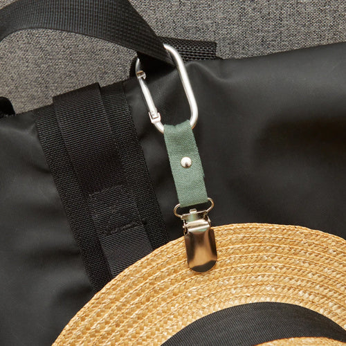 A straw hat clipped to a backpack with the travel hat clip.